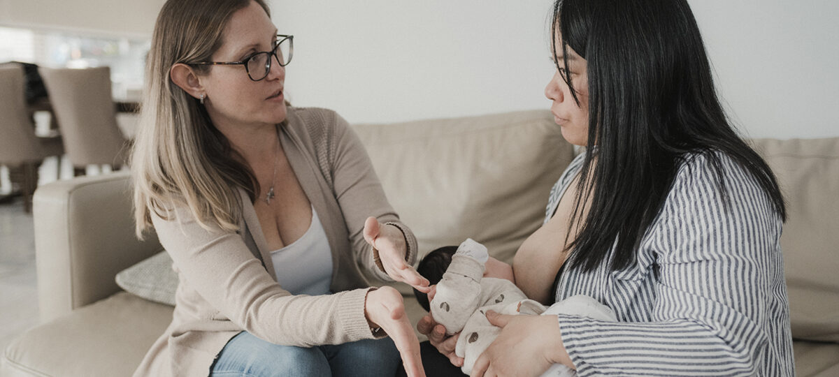 Laurinda instructs a mother on the correct way to hold a baby for breastfeeding